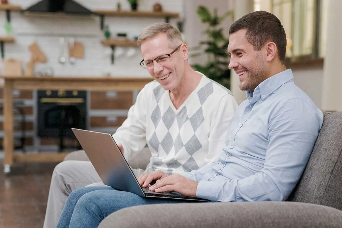 Technician helping middle-aged man customer with a laptop error in the customer's living room